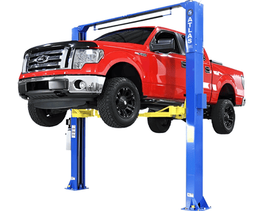 Heavy-duty red pickup truck on blue hydraulic lift for vehicle maintenance.